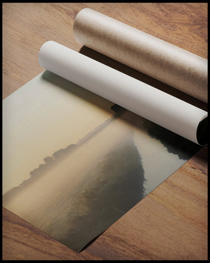 Ein Poster von einer nebligen Landschaft in den Niederlanden, mit einem Wasserkanal und einer Kirche im Hintergrund, gerollt auf einer Holzoberfläche liegend