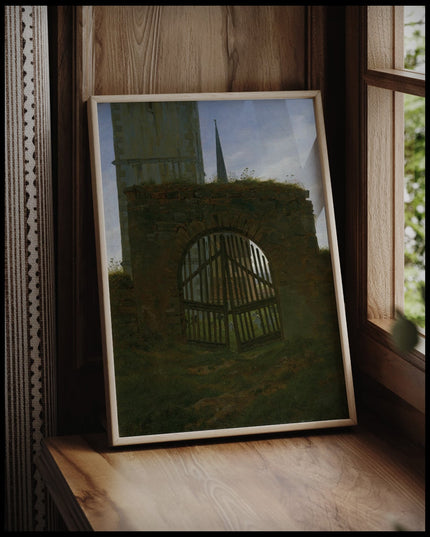 Ein gerahmter Kunstdruck eines Friedhofstors vor einem Fenster an die Wand angelehnt