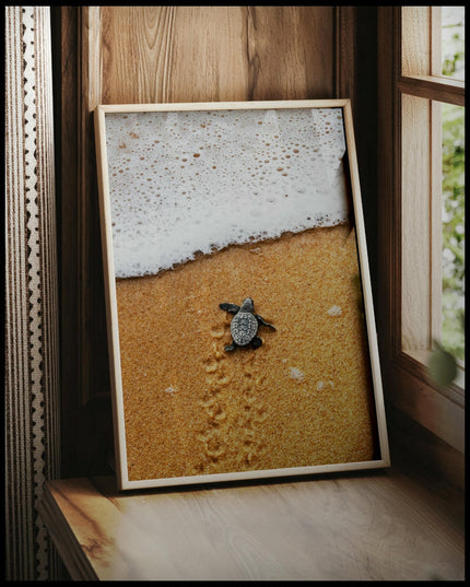 Ein gerahmtes Poster von einer Baby Schildkröte am Strand, die auf dem Weg zum Wasser ist, vor einem Fenster an die Wand angelehnt